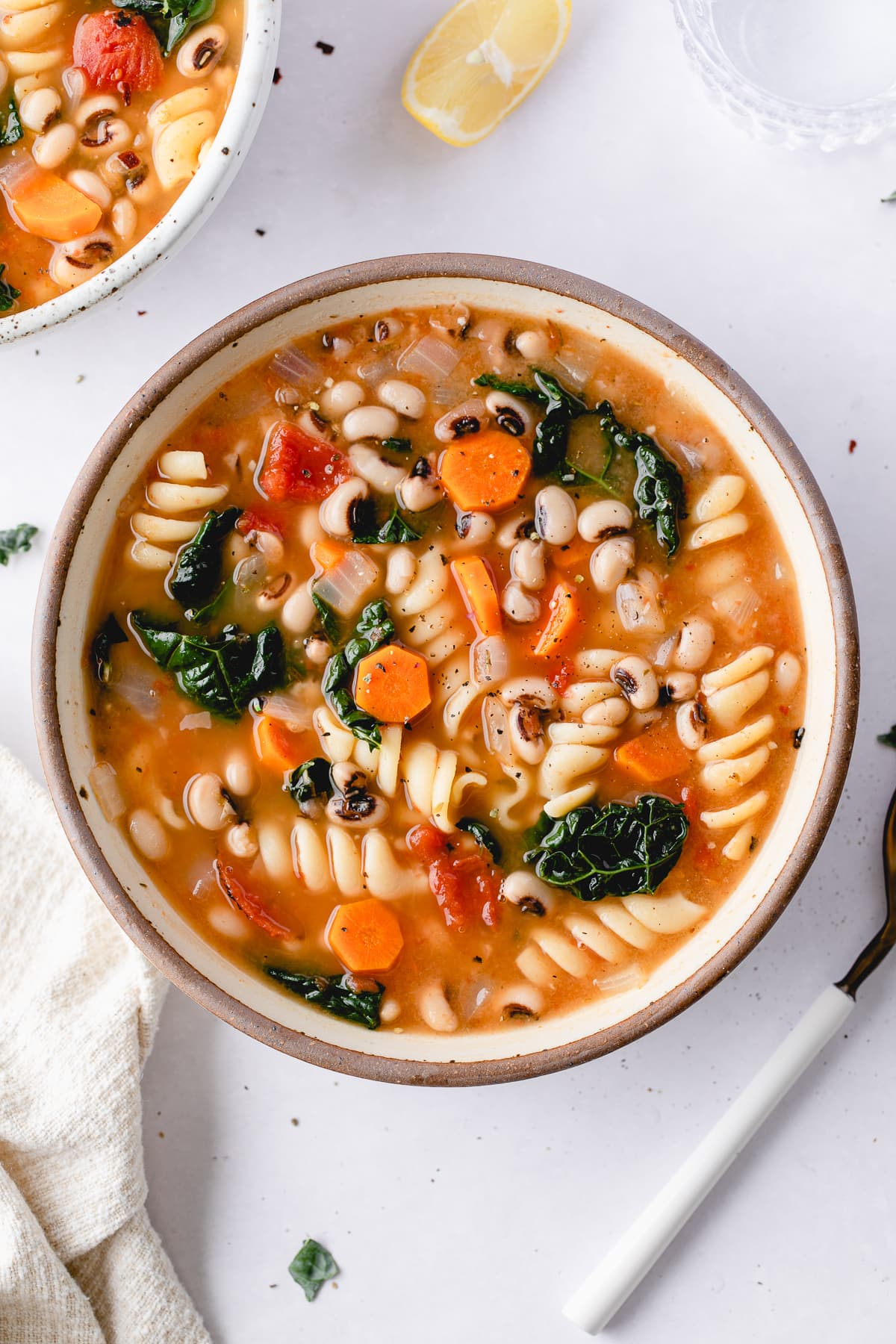 top down view of bowl of healthy pasta and bean soup with items surrounding.