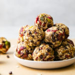 head on view of freshly rolled oatmeal energy bites with pistachios and cranberries on a plate.