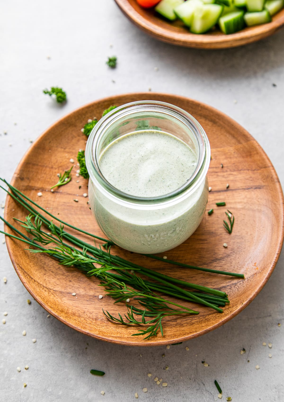 side angle view of glass jar full of creamy hemp seed dressing with items surrounding.