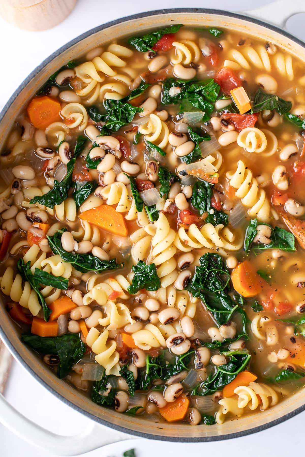 top down view of freshly made pot of pasta and bean soup with kale.