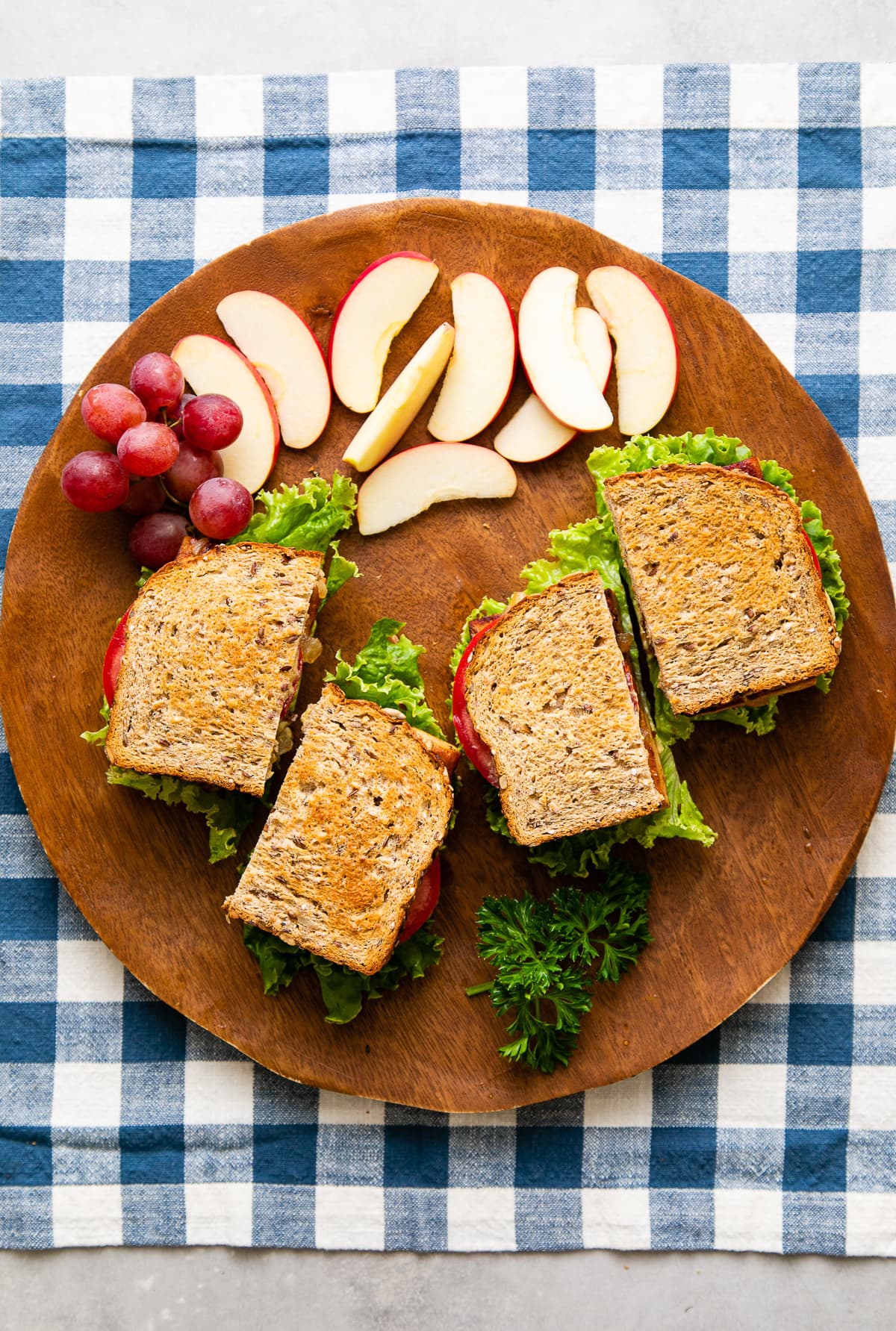 top down view of tofu sandwiches sliced in half on wooden tray with fruit.