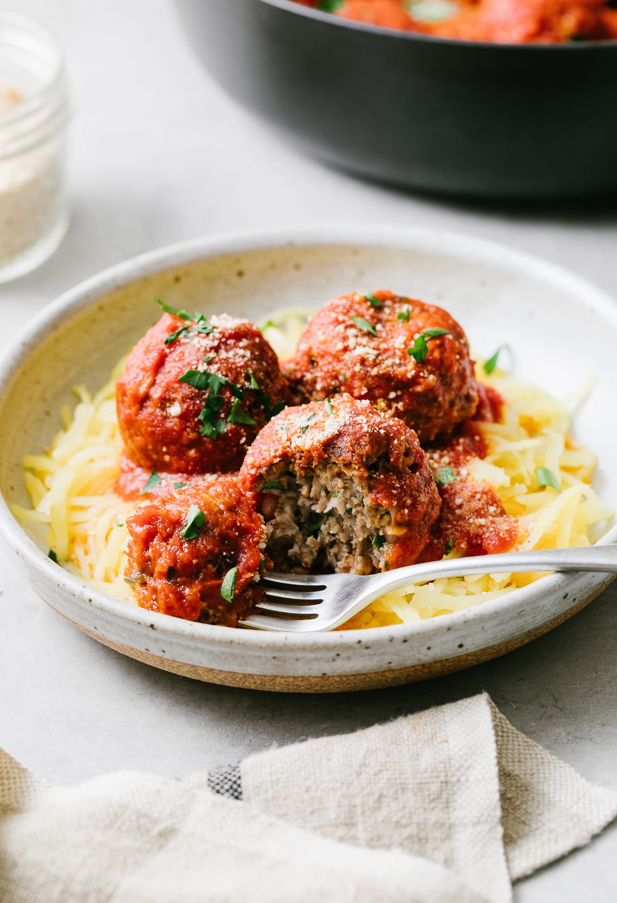 side angle view of spaghetti and vegan meatballs in a bowl with fork holding a bite.