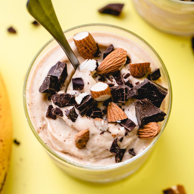 top down view of non dairy chunky monkey in a glass with toppings and spoon.