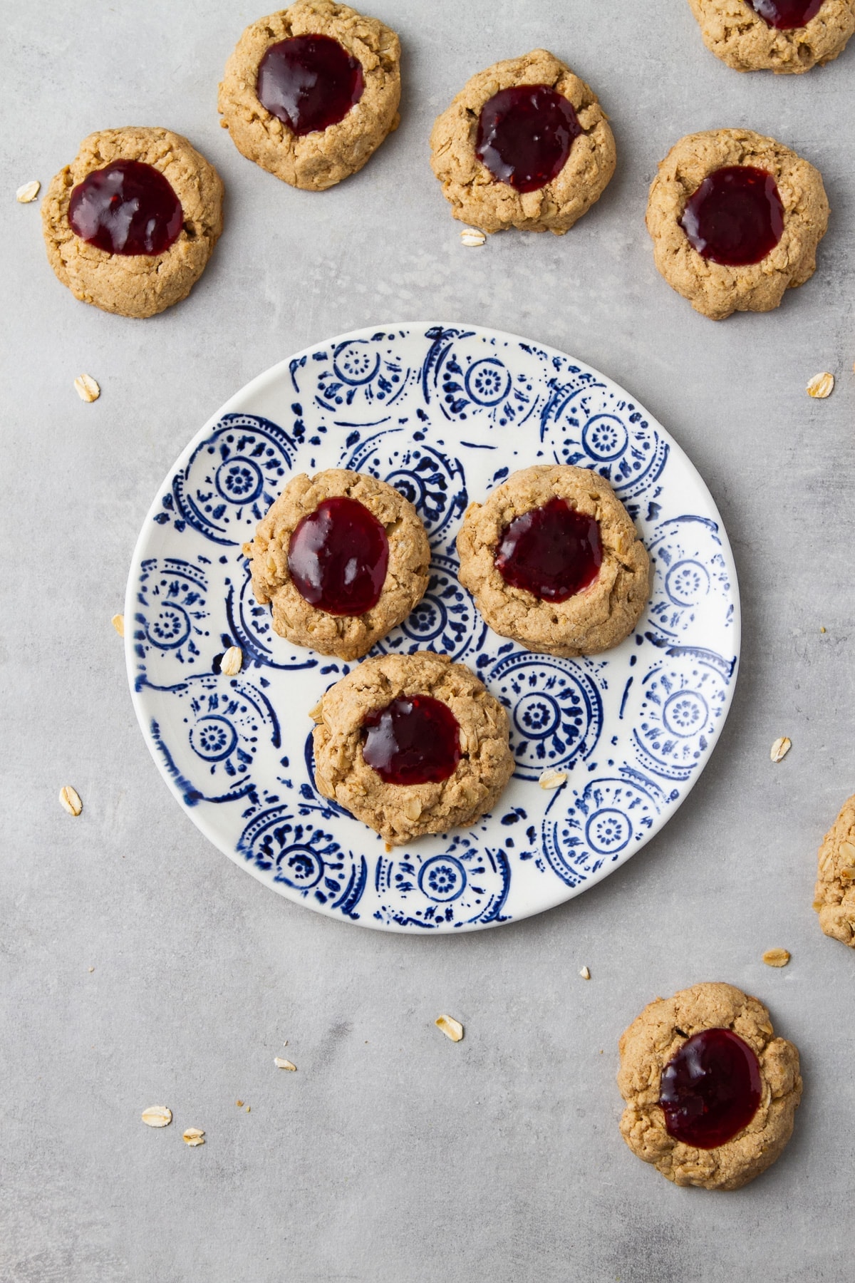 top down view of freshly made vegan oat jam thumbprint cookies on a small plate.
