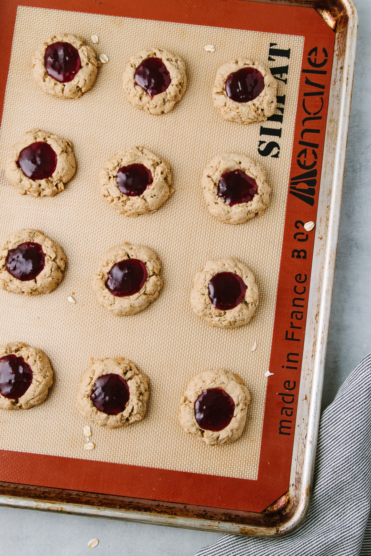 top down view of healthy vegan thumbprint cookies on a rimmed a baking sheet. 