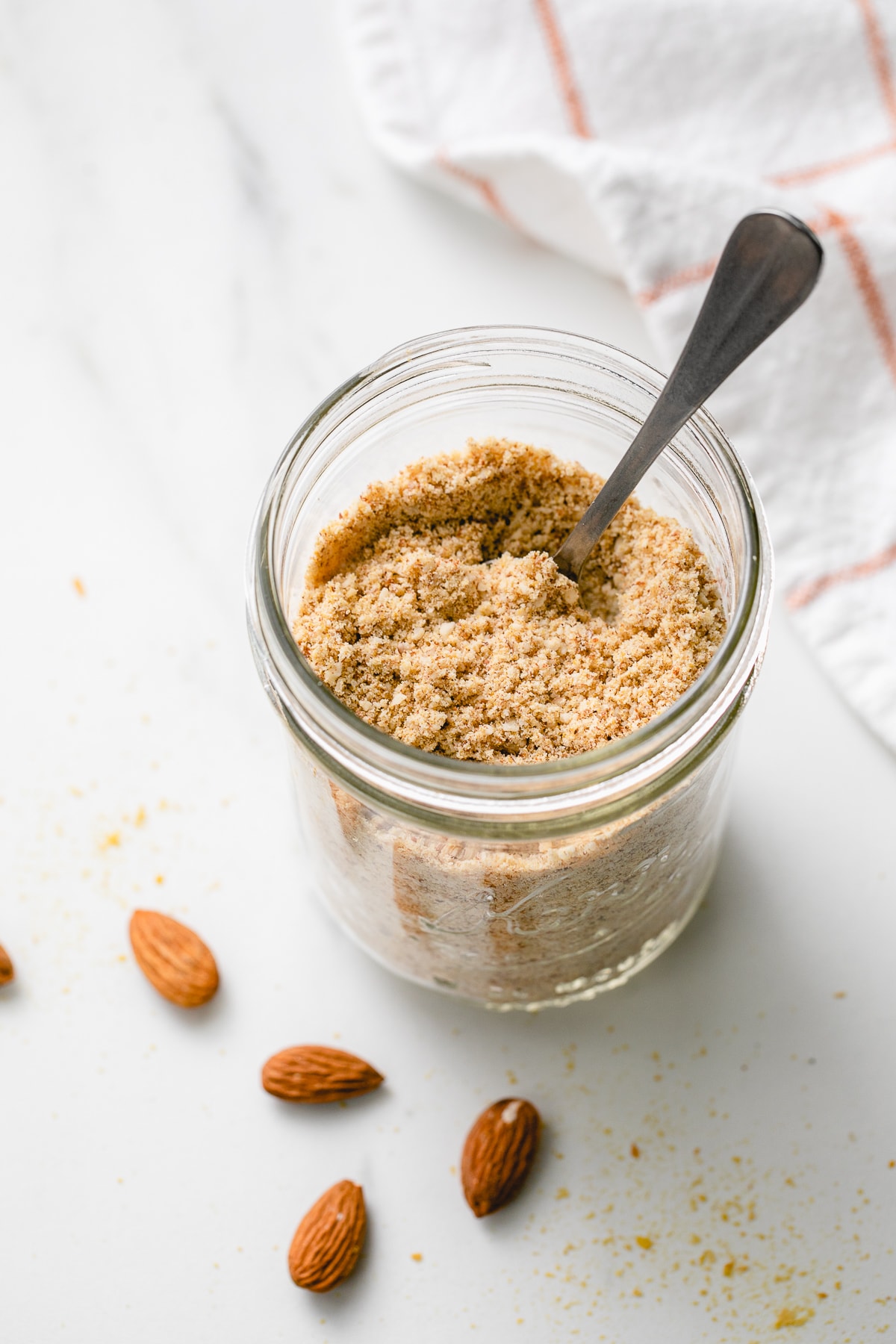 top, side angle view of almond parmesan in a mason jar with spoon.