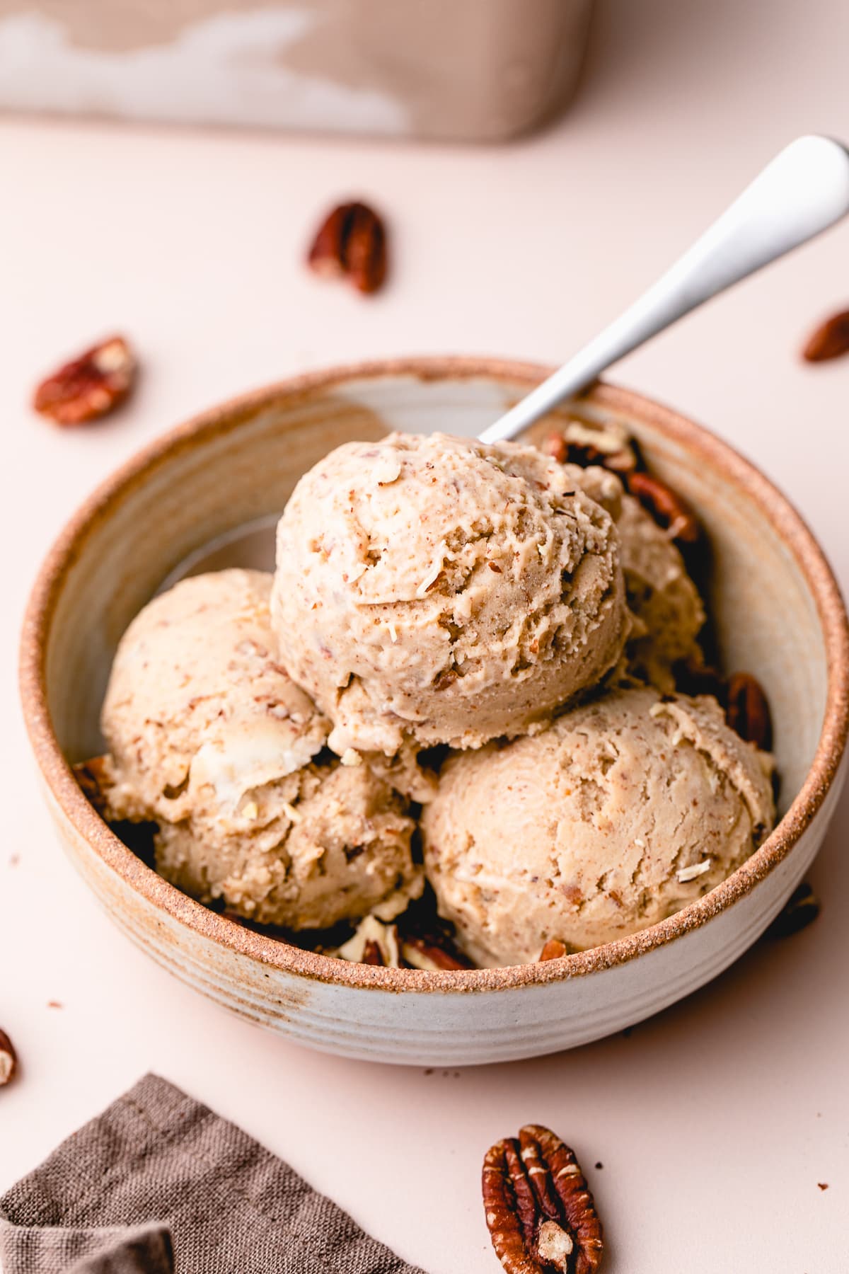side angle view of healthy vegan butter pecan ice cream scoops in a bowl.