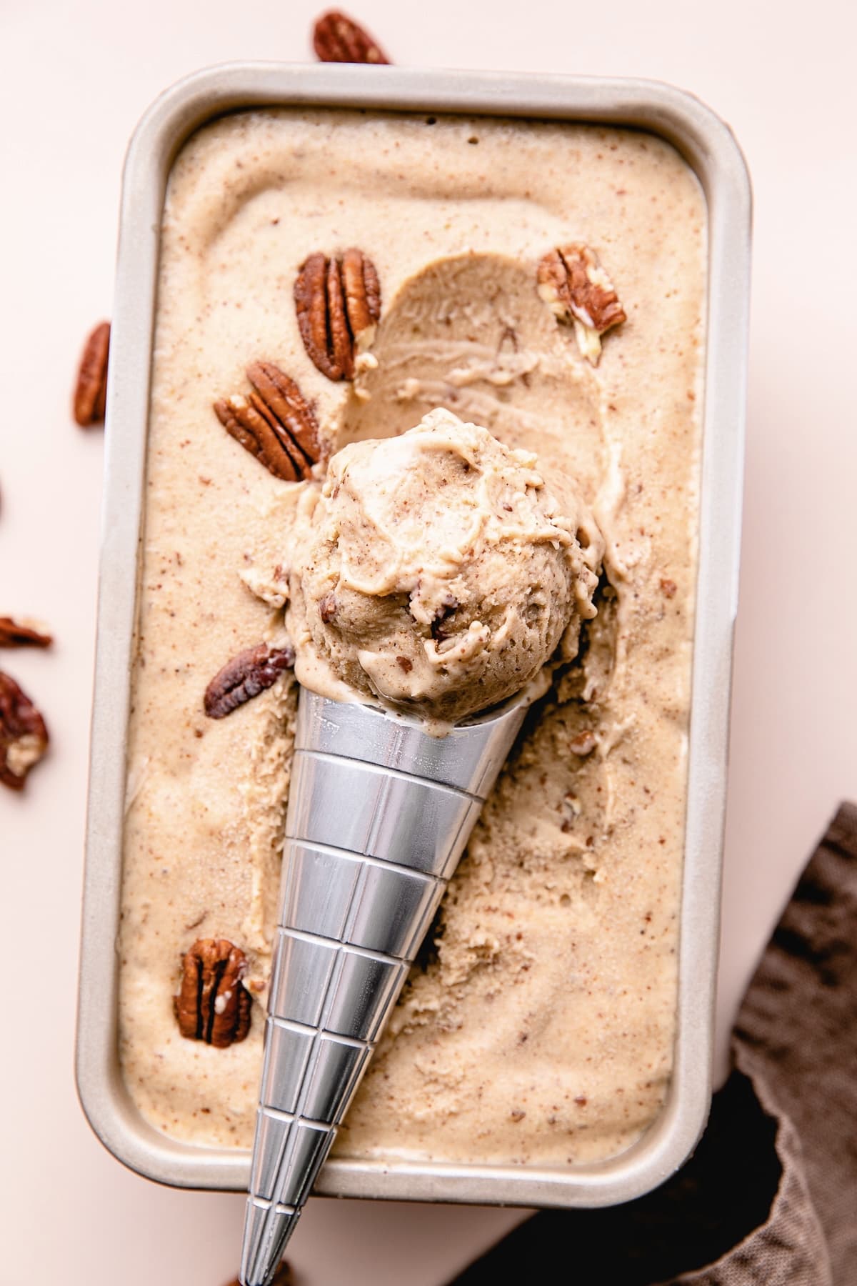 top down view of vegan butter pecan ice cream scooped with ice cream scoop resting on frozen ice cream.