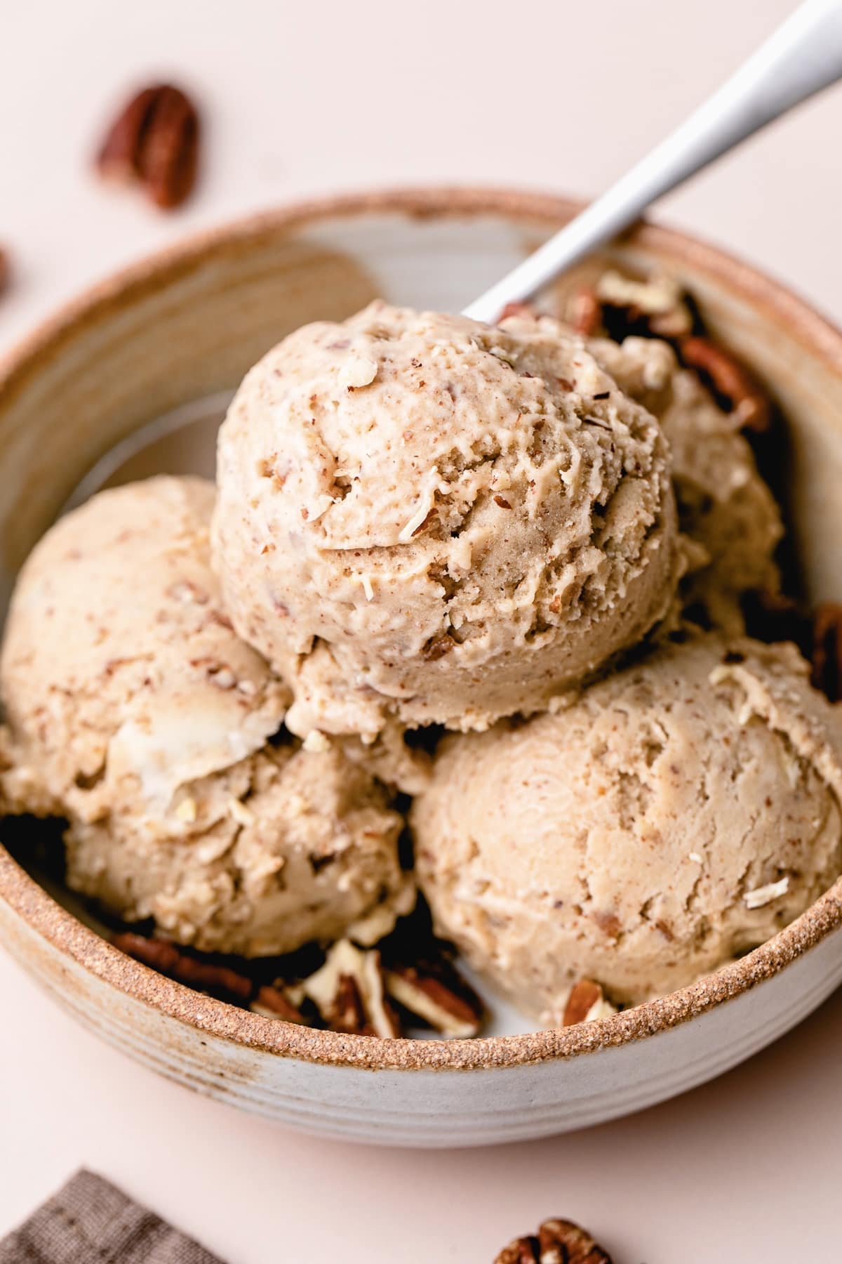 side angle view of healthy vegan butter pecan ice cream scoops in a bowl.