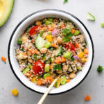 top down view of healthy vegan quinoa salad in a bowl with items surrounding.