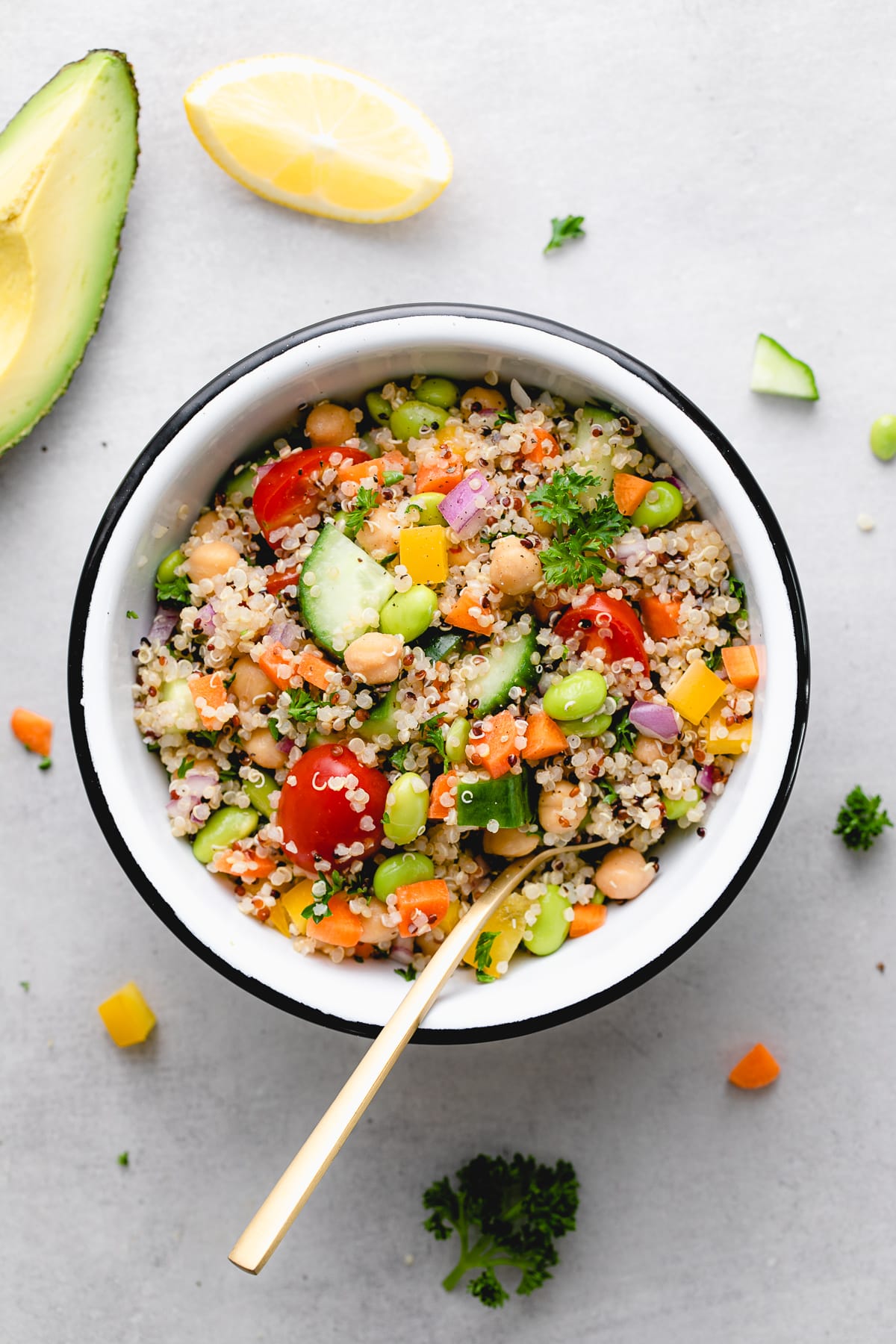top down view of healthy vegan quinoa salad in a bowl with items surrounding.