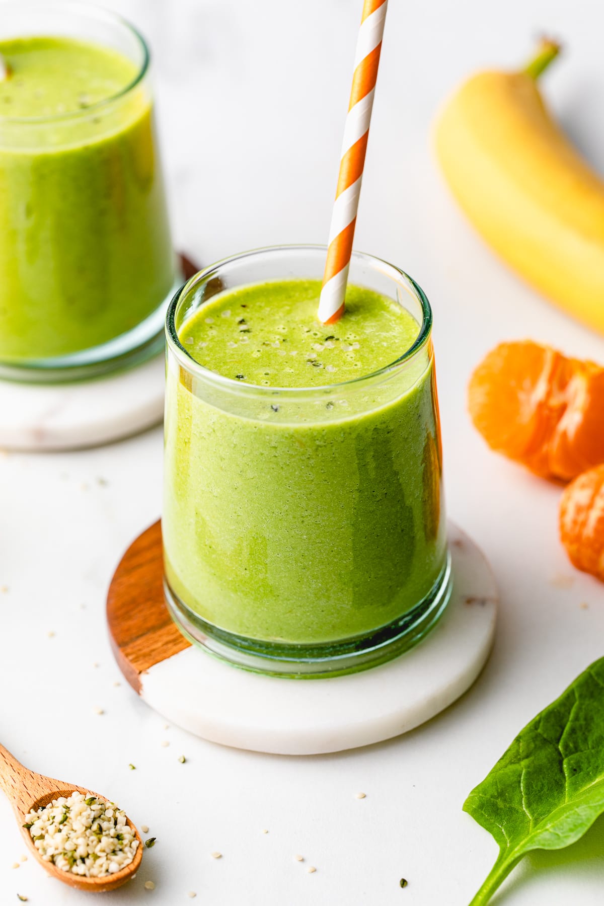 side angle view of hemp smoothie in a glass with straw and items surrounding.