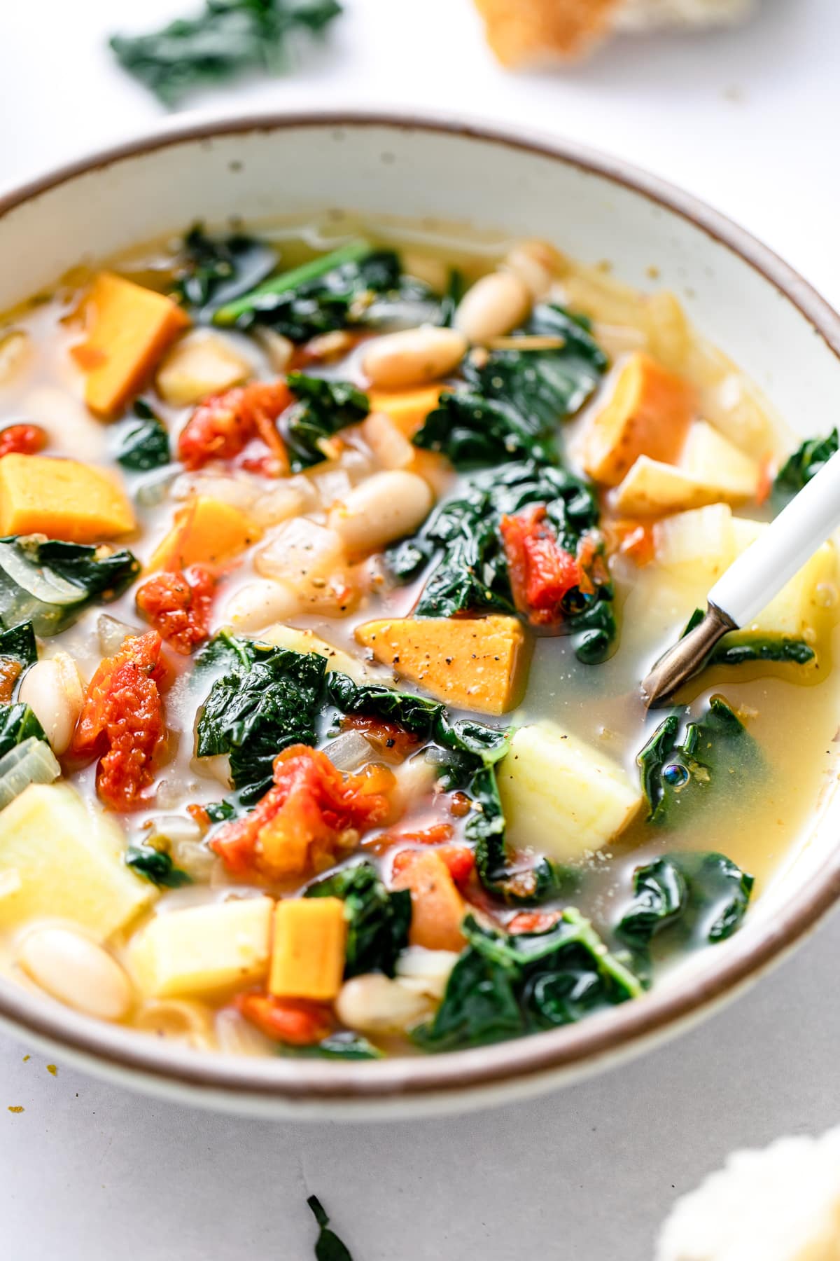 side angle view of sweet potato kale soup in a bowl with spoon.