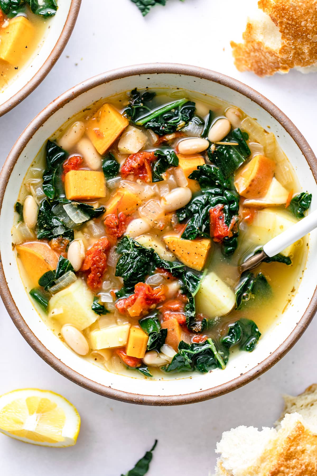 top down view of healthy sweet potato kale soup in a bowl with items surrounding.