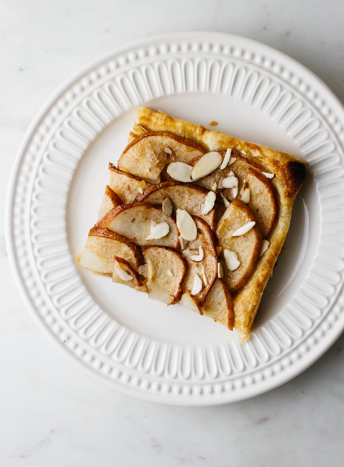 top down view of slice of pear tart on a plate.