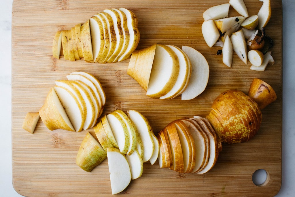 top down view of sliced pears on wooden cutting board.