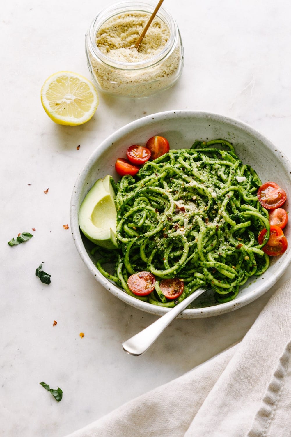 a side view of a bowl of zucchini noodles tossed with spicy kale pesto