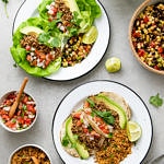 top down view of vegan street tacos on white plates with items surrounding.
