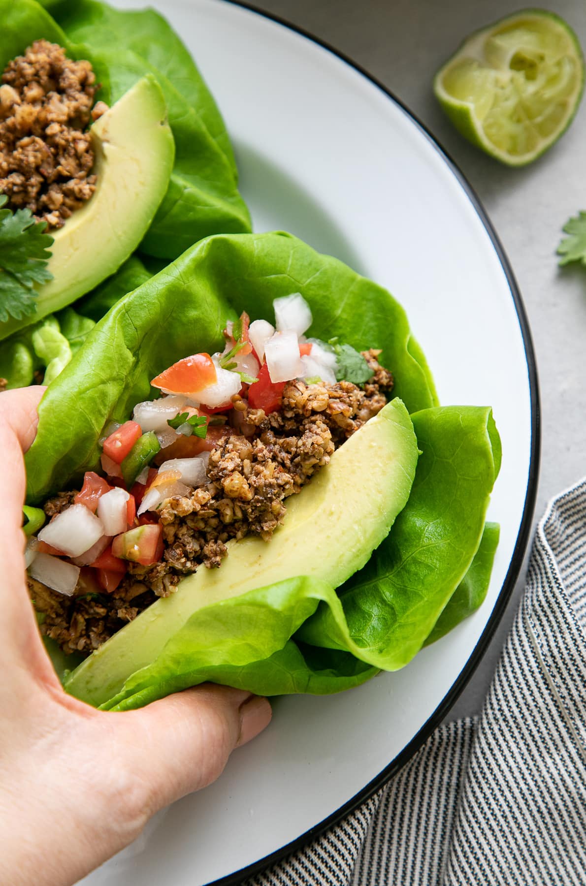 top down view of hand holding lettuce vegan street tacos with walnut meat.