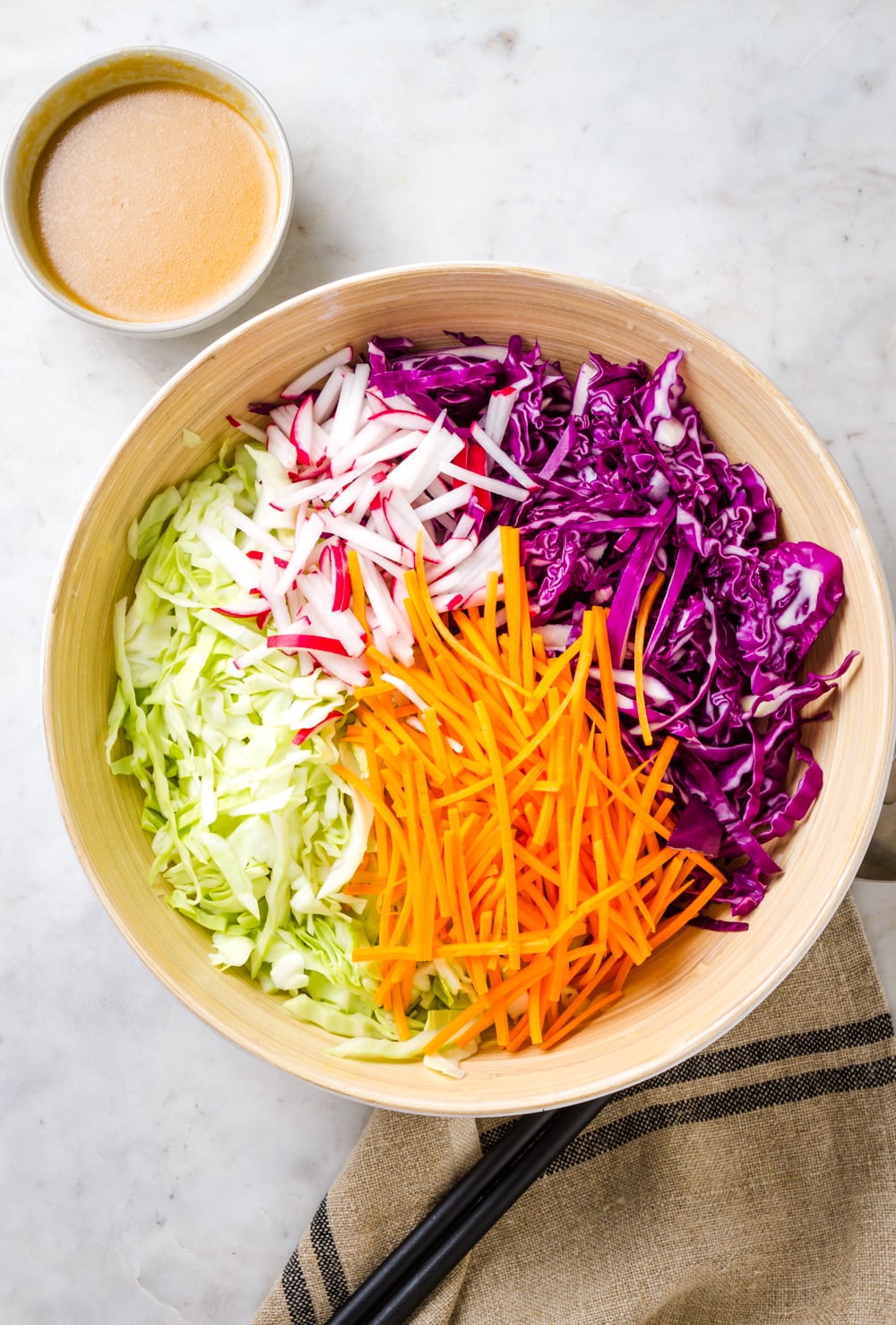 top down view of a mixing bowl with ingredients added for making slaw salad just before mixing.