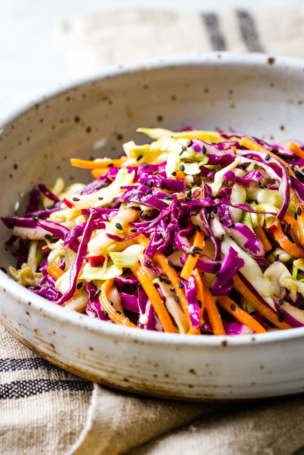 side angle view of a serving of crunchy asian slaw salad in a bowl.
