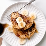 top down view of plated vegan banana french toast with syrup being poured over top.