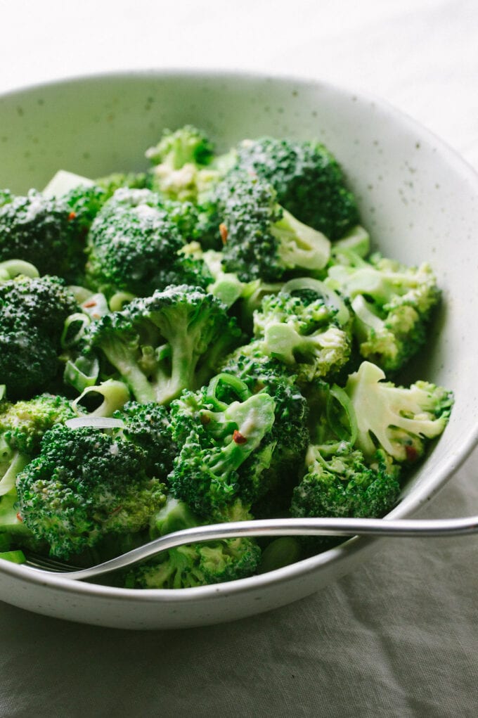 side angle view of steamed broccoli with tahini miso dressing.
