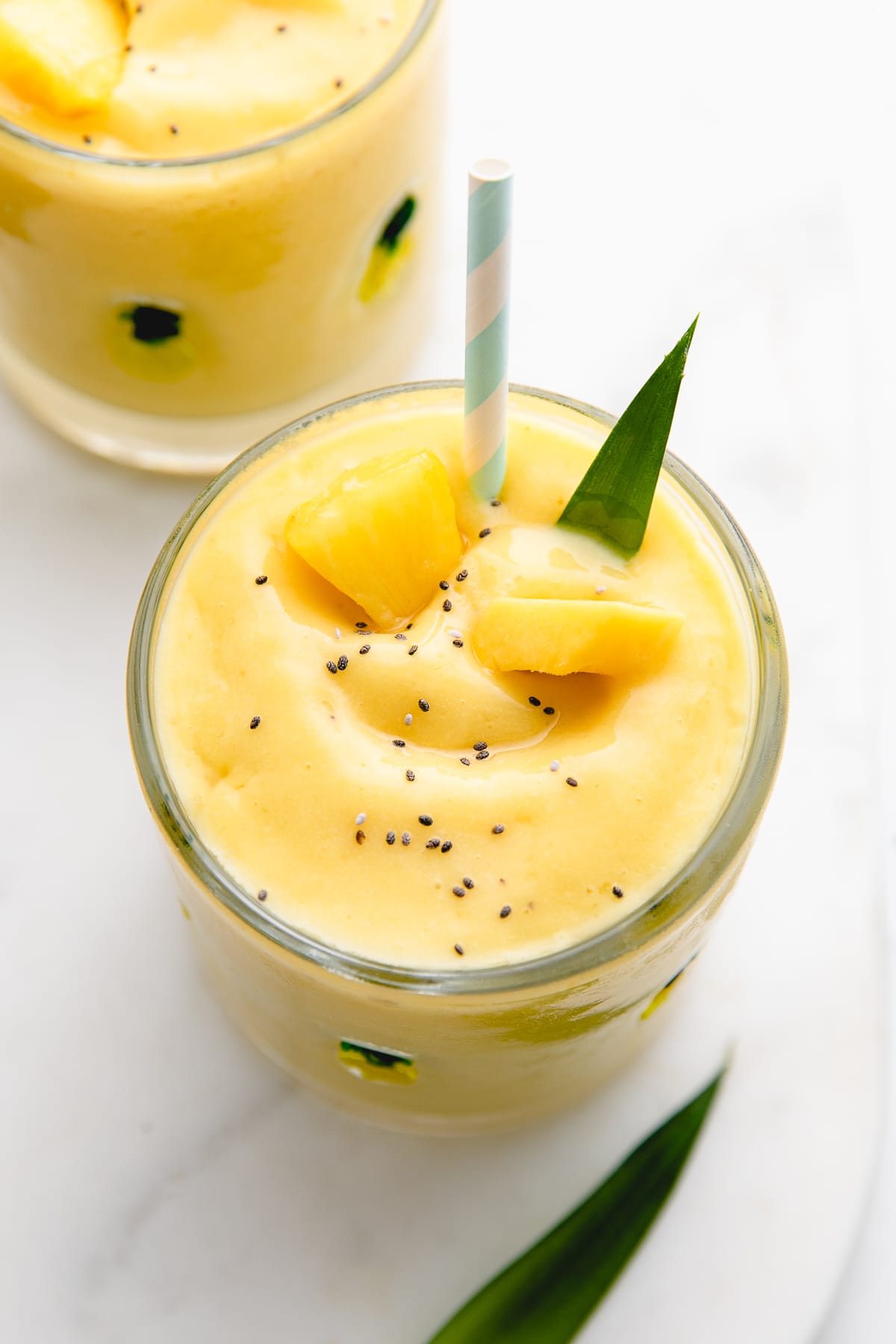 top down view of refreshing mango pineapple banana smoothie in a glass.