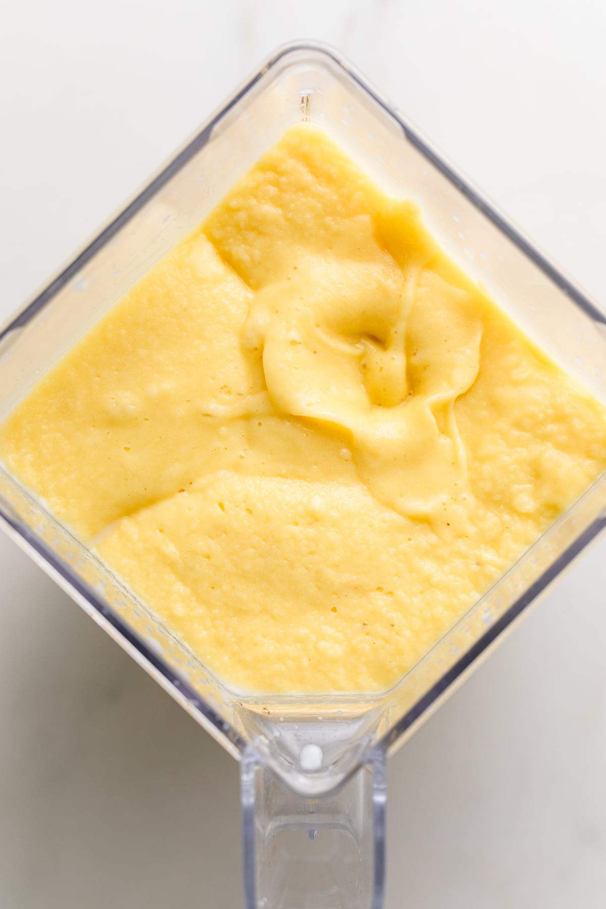 top down view of blender cup filled with mango pineapple banana smoothie.