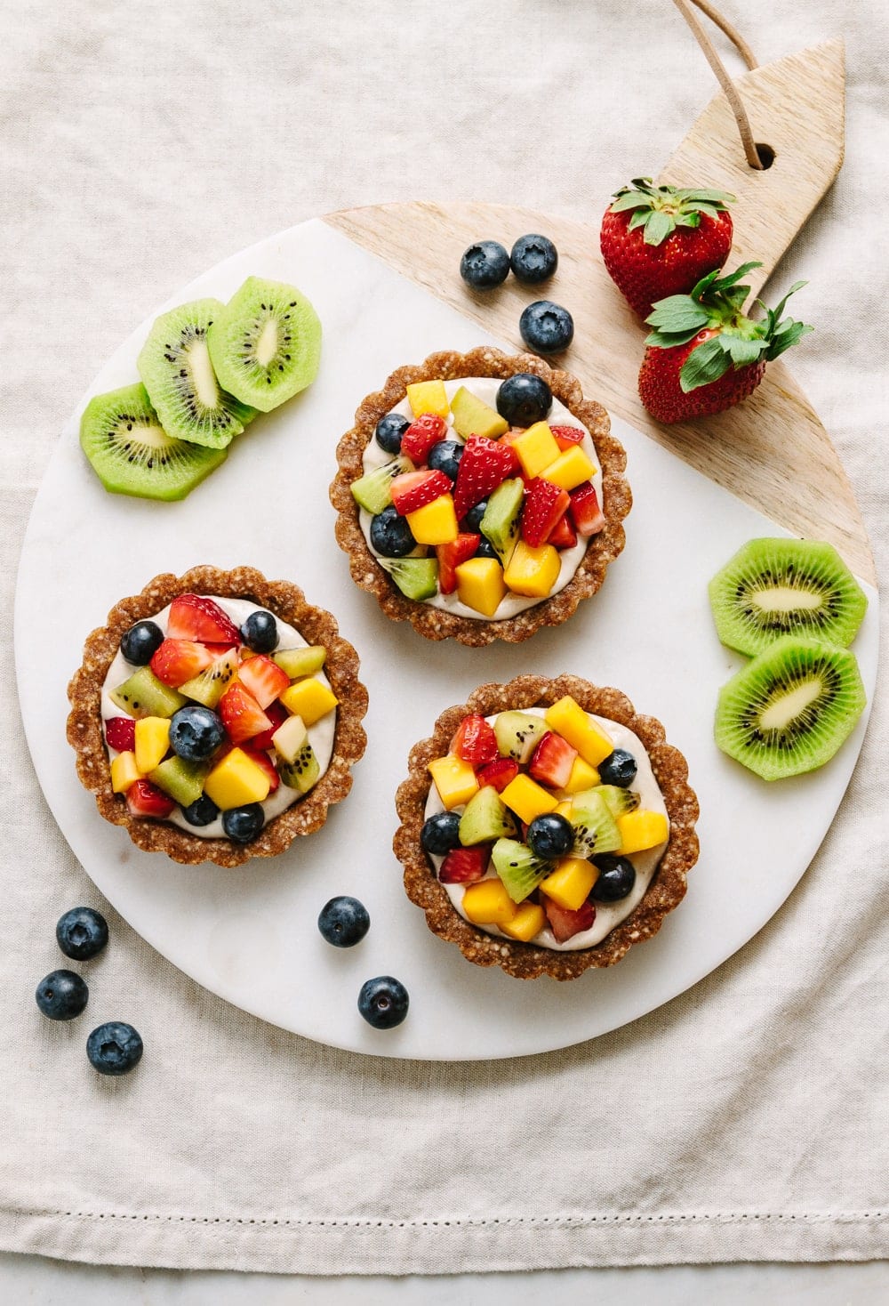 top down view of raw fruit tart on a circle marble serving board.