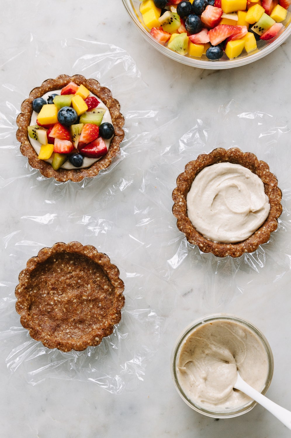 top down view of the process of assembling raw vegan fruit tarts.