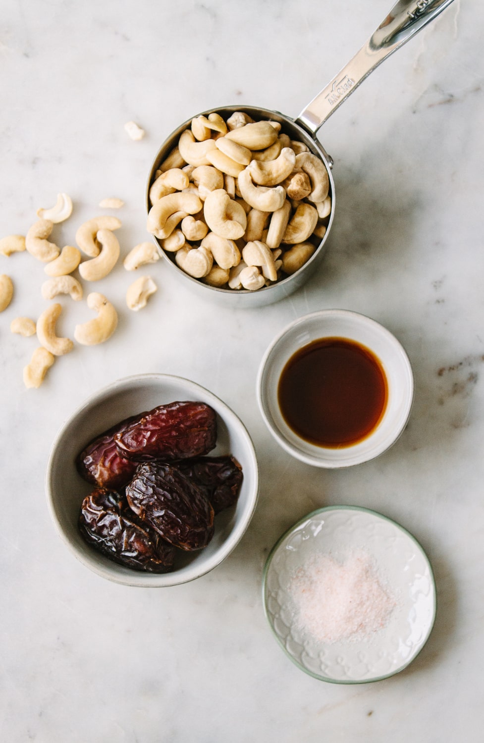 top down view of homemade cashew sweet cream in a bowl next to bowls full of raw cashews and fresh dates.