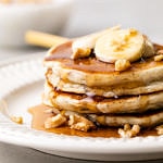 head on view of stacked almond flour banana gluten free pancakes on a plate with items surrounding.