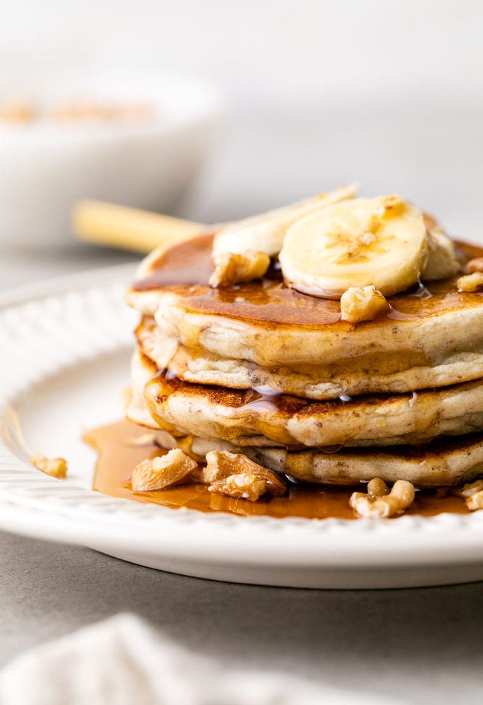 head on view of stacked almond flour banana gluten free pancakes on a plate with items surrounding.