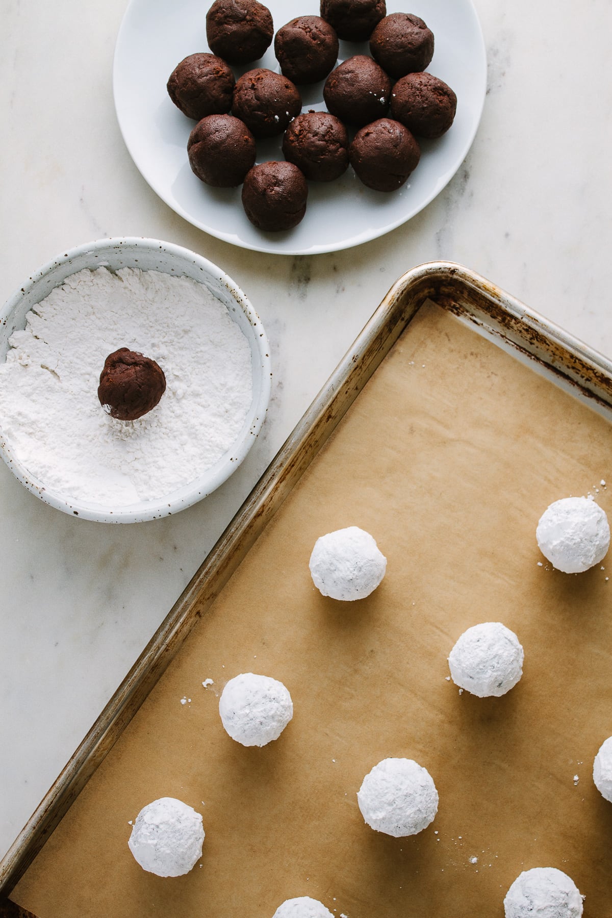 top down view of chocolate crinkle cookies on a rimmed baking sheet.