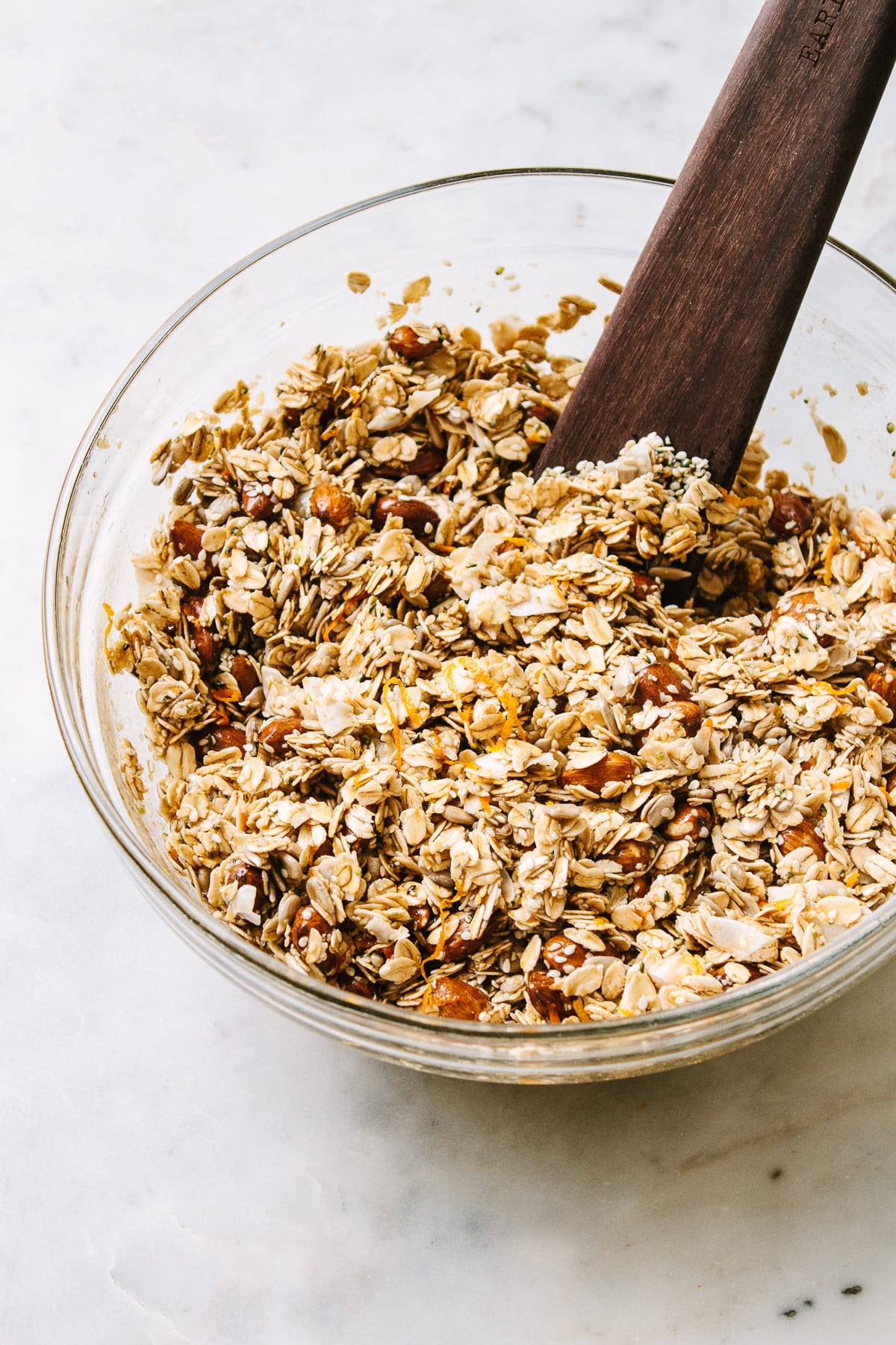 side angle view of showing the process of mixing the ingredients together to make ginger orange granola.