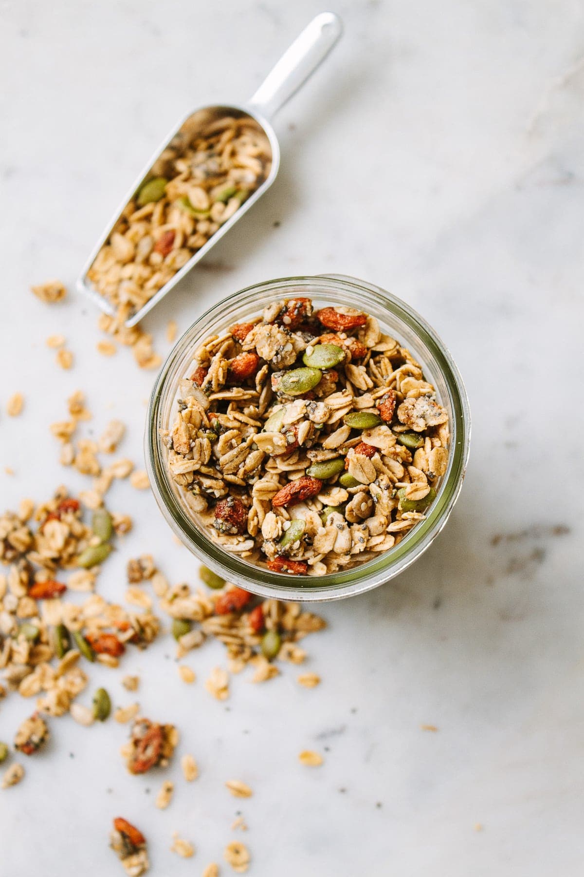 top down view of seeds and goji berry granola in a mason jar with items surrounding.