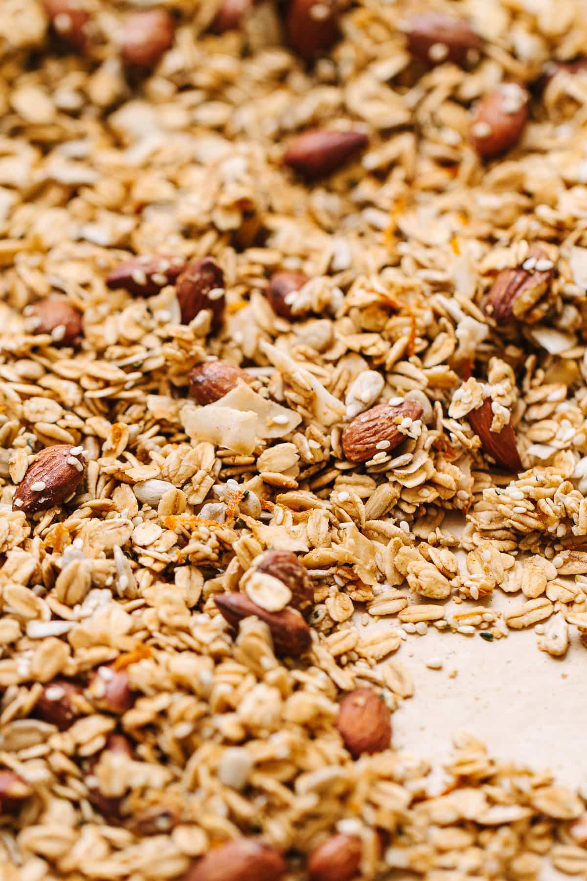 side angle view of freshly made orange ginger granola on a baking sheet.