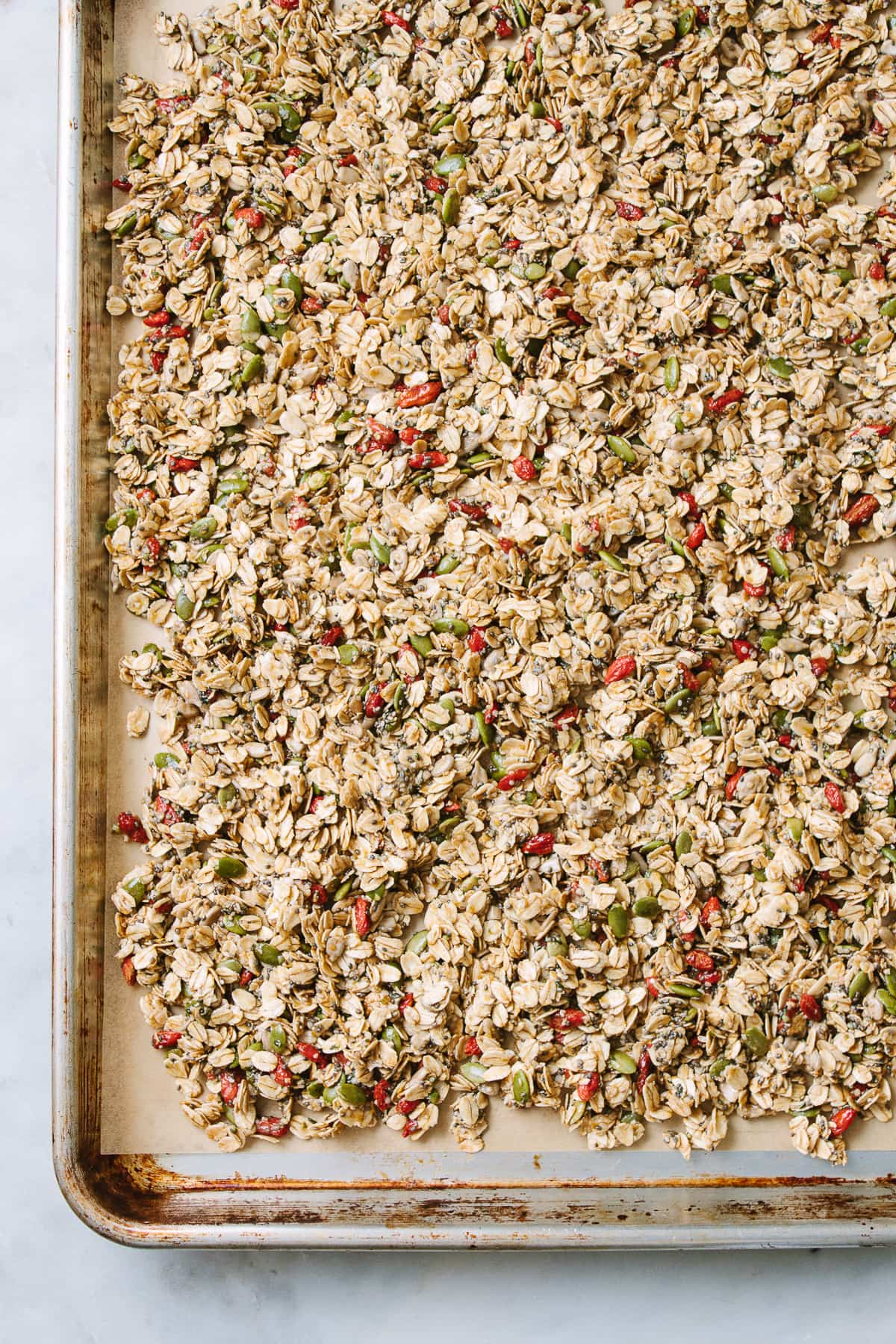 top down view healthy granola layered on a baking sheet before going into the oven.