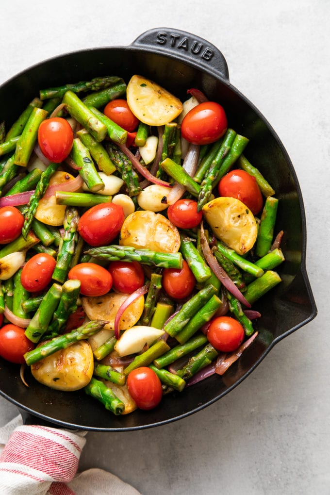 top down view of freshly cooked asparagus and tomato medley in a skillet.