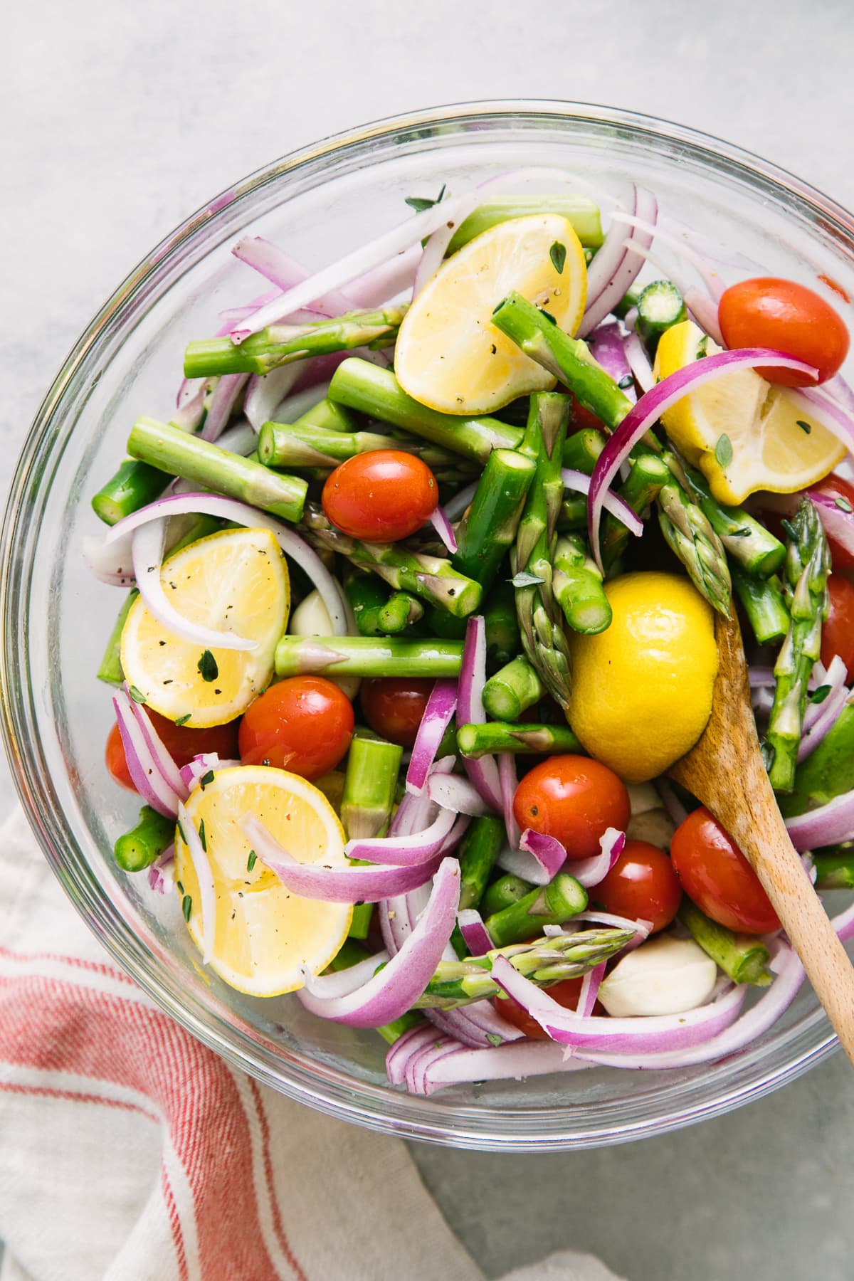 top down view of asparagus and tomato medley ingredients mixed together in a glass bowl.