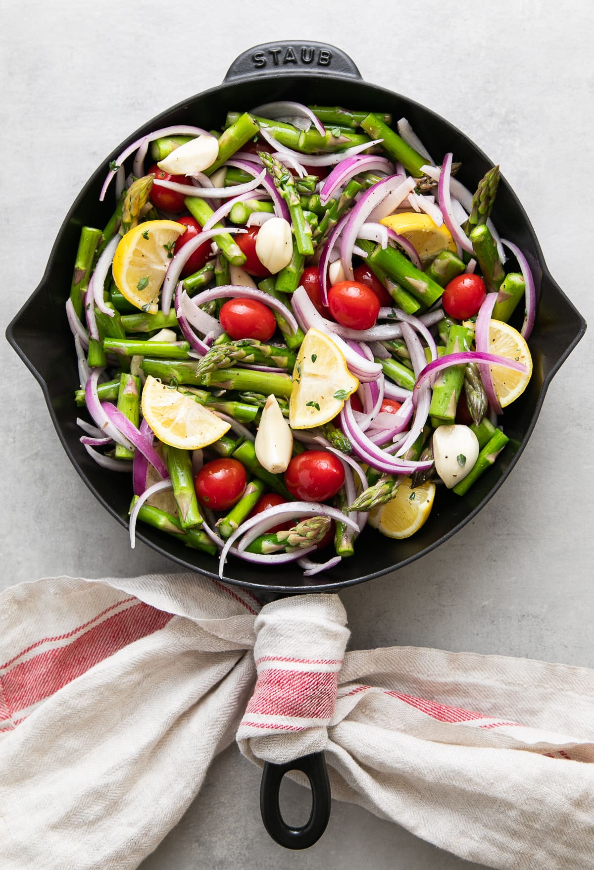 top down view of asparagus and tomato medley ingredients added to cast iron skillet to cook.