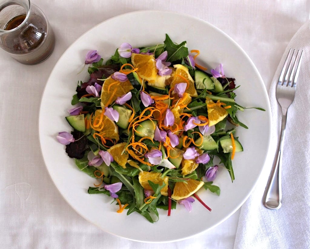 top down view of spring salad with edible flowers and dandelion greens.