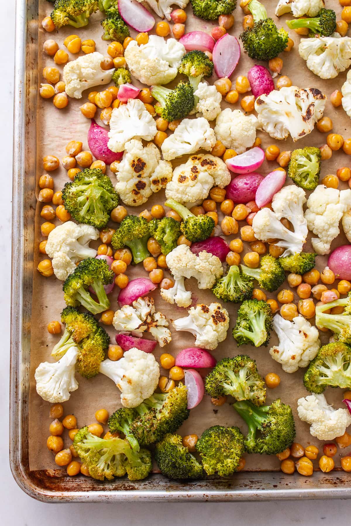 top down view of freshly roasted veggies for vegan buddha bowl on a baking sheet.