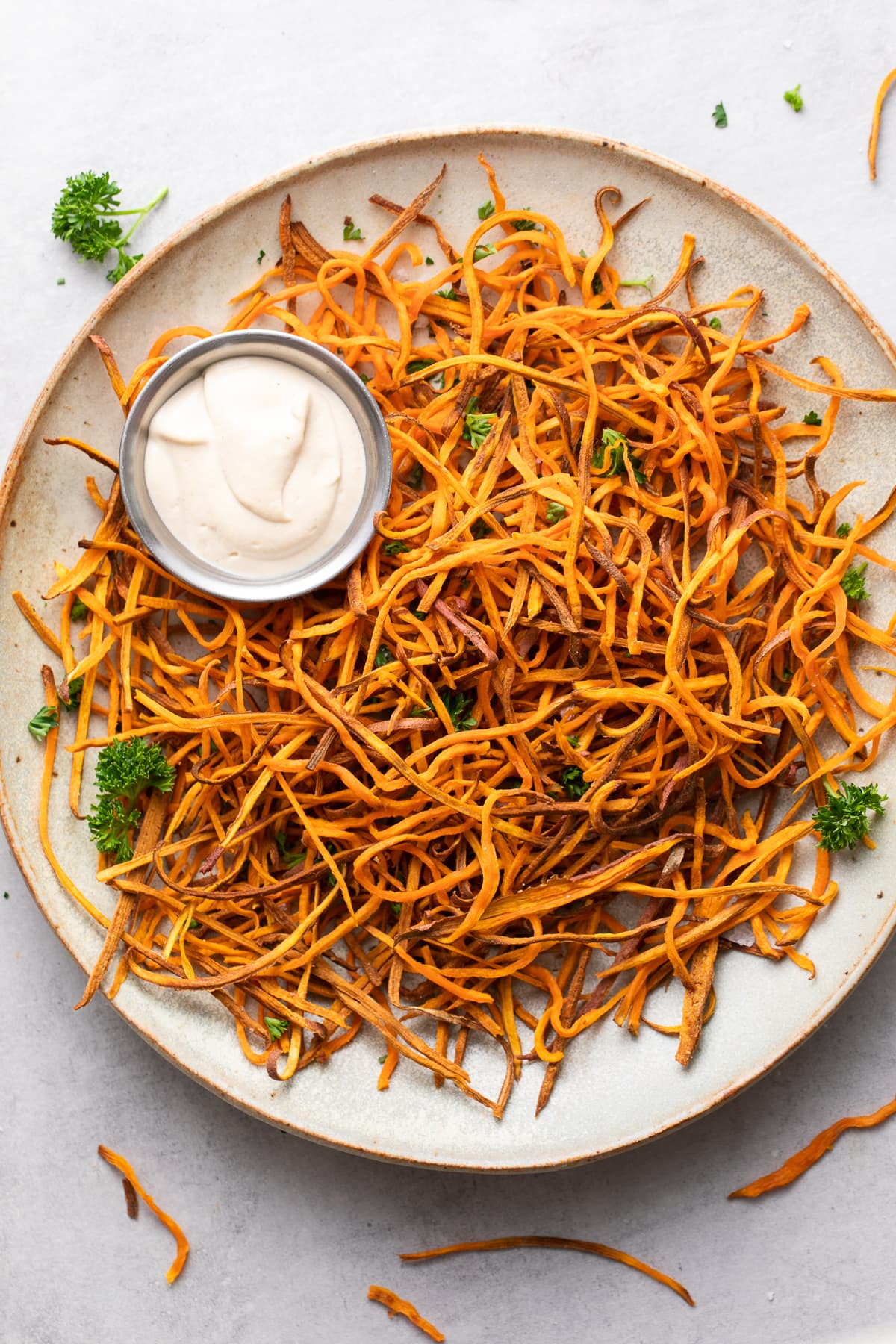 top down view of plate of freshly made baked crispy sweet potato shoestring fries curly style.