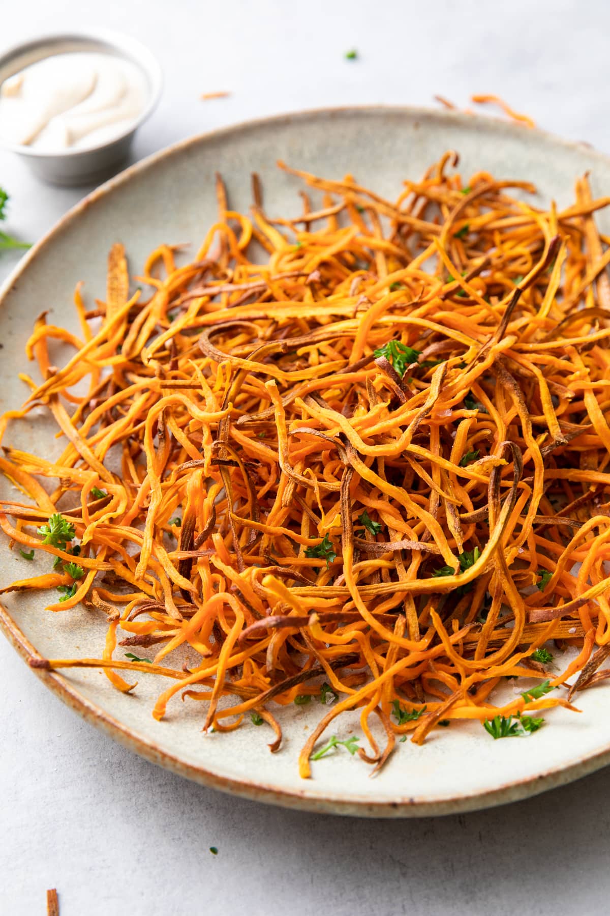 side down view of plate of freshly made baked crispy sweet potato shoestring fries curly style.