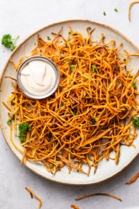 top down view of plate of freshly made baked crispy sweet potato shoestring fries curly style.