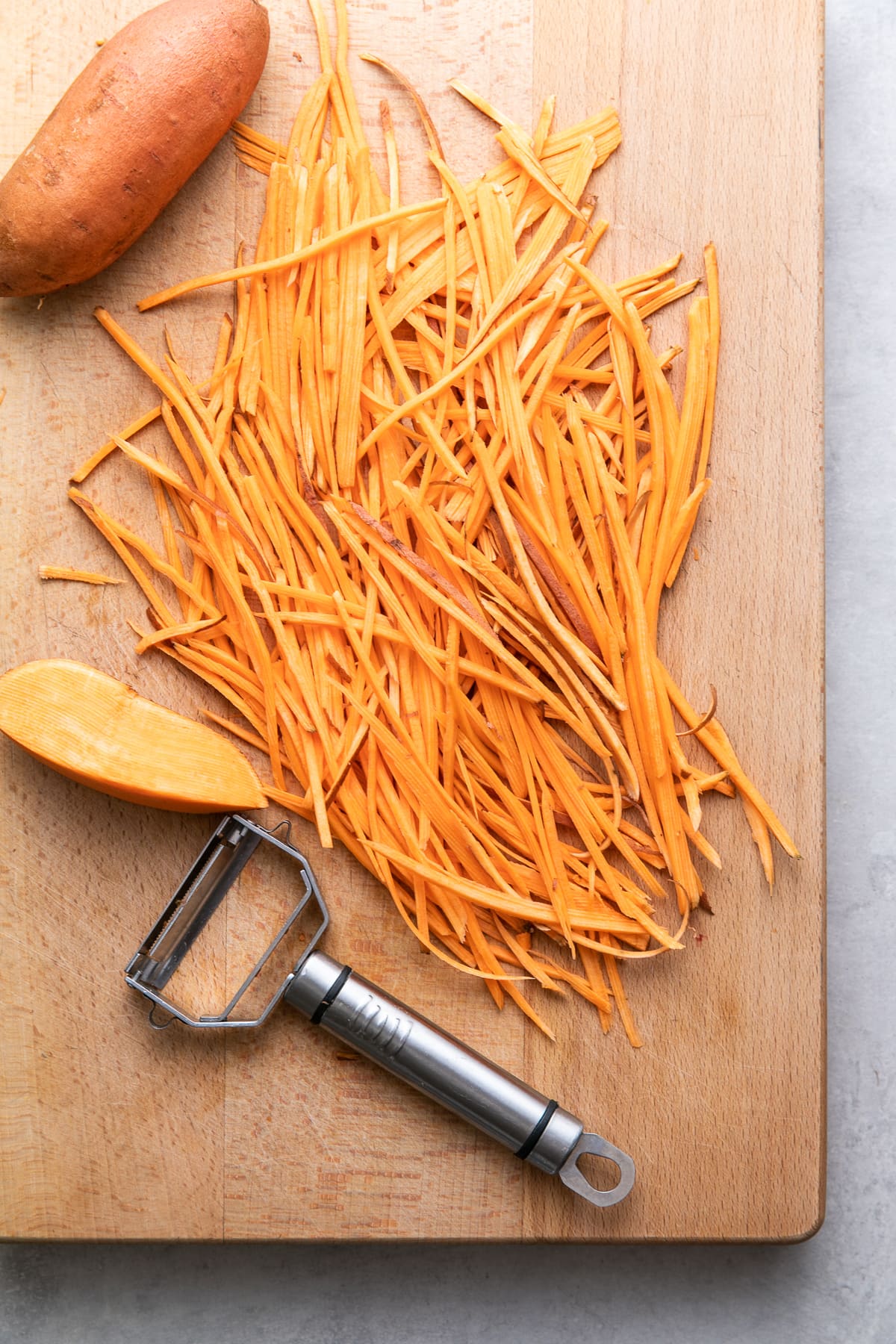 side angle view of julienned sweet potato on a cutting board.