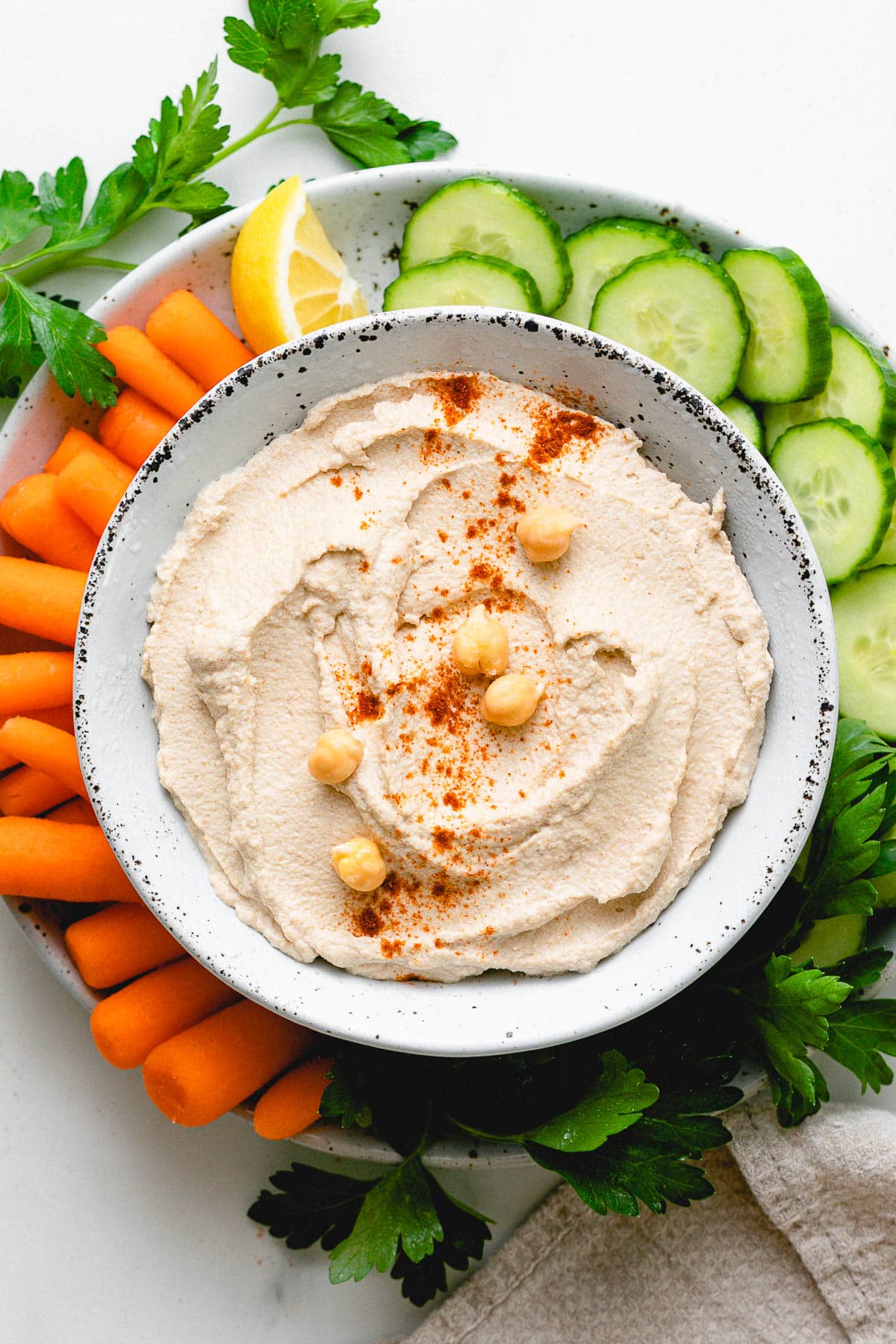 top down view of raw sprouted hummus in a bowl with fresh veggies surrounding.