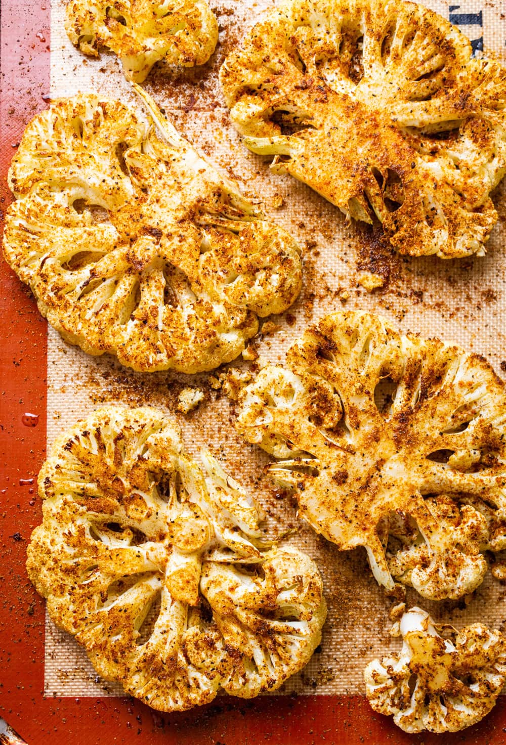 top down view of roasted cauliflower steaks on a baking sheet.